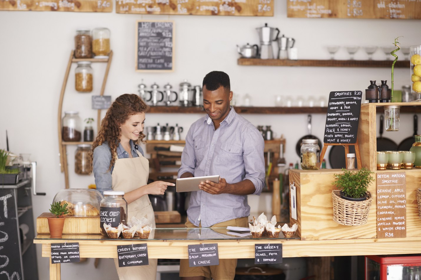Cropped shop of a handsome coffee shop owner showing a waitress the ropes