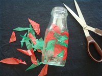 Covering a small recycled glass jar with tissue cuttings to make a vase