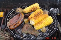 A grill with several pieces of corn on the cob cooking