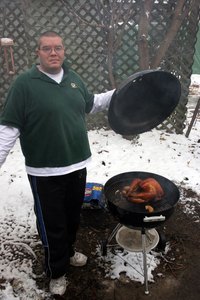 Cooking a turkey on a chargoal grill.