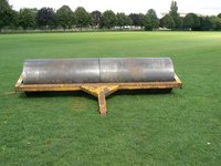 Rollers flatten soil under their weight as they are pulled over a field.