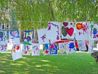 Art painted by kids, hanging on a line to dry.