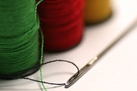 A needle and embroidery thread are used to embroider on paper.