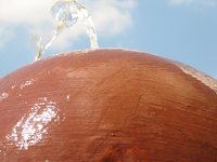 A cement ball fountain adds ambiance to a garden or patio.