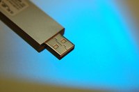 A memory stick transfers a stitching file to an embroidery machine.