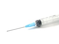 A syringe is used to inject ink into the cartridge.