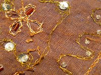A sequin design is sewn onto a piece of fabric.