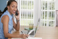 Woman talking on phone while using laptop computer.