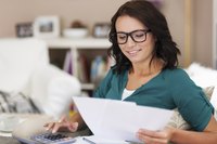 Woman looking over invoices with a calculator