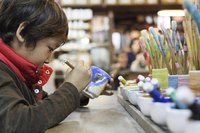 Young boy painting pottery.