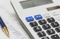 A calculator, pen and financial papers.