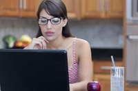 A woman working at her laptop in the kitchen.