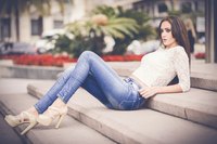 Woman wearing tight jeans and heels on steps outside.