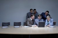 Group of employees looking at laptop during meeting.