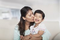 Mother kissing young daughter on the cheek.