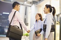 Two saleswoman shaking the hand of a businessman.