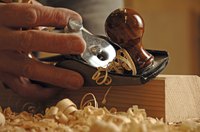 Woodworker shaving a piece of wood with a block plane.