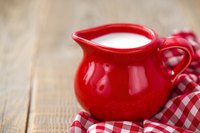 A pitcher of cream on a gingham tea towel.