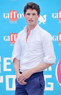 Eddie Redmayne twist-rolls his shirtsleeve to partially expose cuffs.