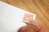 A close-up of a man placing a stamp on an envelope.