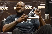 Sports star Shaquille O'Neal holds up a Reebok sneaker at an event