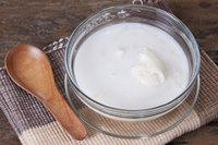 A bowl of coconut yogurt and a wooden spoon on a towel.