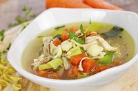 A bowl of chicken soup with vegetables.
