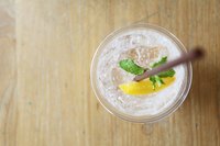 An overhead view of a vodka soda with a lemon wedge and sprig of fresh mint.