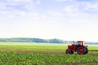 A red tractor plows a field.