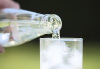 Glass of water being poured from bottle.