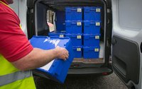 A delivery driver loading bins into a cargo van.