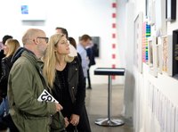 Gallery visitors examing and discussing art.