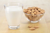 A glass of almond milk and a bowl of almonds.