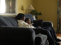 A mother and son watching tv together on the sofa.