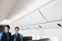 Two stewardesses are standing on a plane.