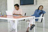 Woman talking on the phone while her partner works on his laptop.