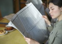 A woman is reading a newspaper.