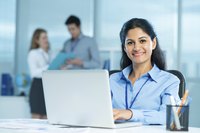 Image of a businesswoman smiling working on her computer.