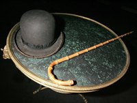 Chaplin's derby and cane are both costume pieces and comedy props.