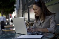 A businesswoman using a laptop at an outside cafe.