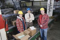 Manager standing beside two employees in warehouse