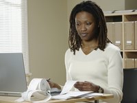 A female accountant examines reciepts and works on her laptop computer