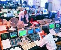 Stock brokers in front of numerous computer screens.