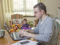 A father working on his laptop at the dining room table.