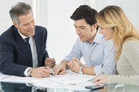 A couple signing documents, sitting next to a mortgage lender