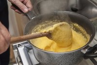 A man stirring while cooking a pot of polenta.