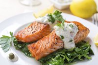 Plate of grilled salmon with sauce drizzled on top of it.
