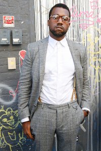 Kanye West creates a look by pairing suspenders with a button-up shirt and eyeglasses.