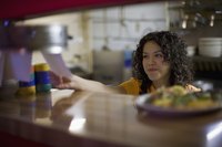 Waitress checking food order in kitchen.