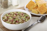 Bowl of ham and bean soup beside cornbread.